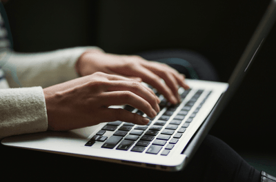 Hands typing on laptop keyboard